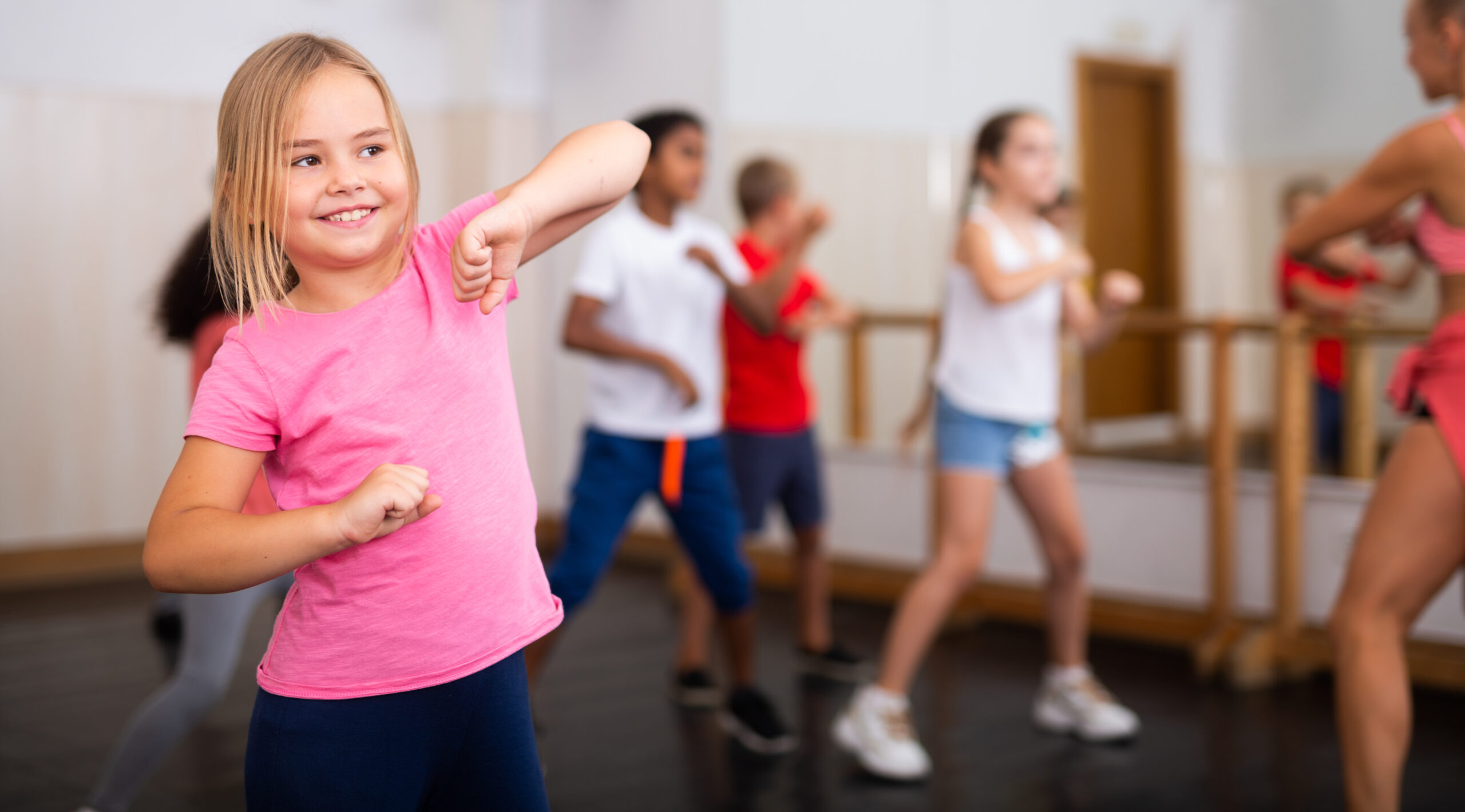 Portrait,Of,Cheerful,Preteen,Girl,Practicing,Dance,Movements,With,Group